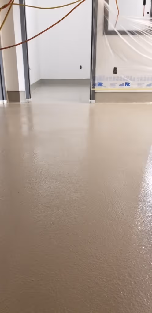 Professional industrial epoxy floor coating installation at Highlands Ranch manufacturing plant showing smooth solid gray high-performance seamless epoxy flooring system with no flakes applied by Hugo's Concrete contractors