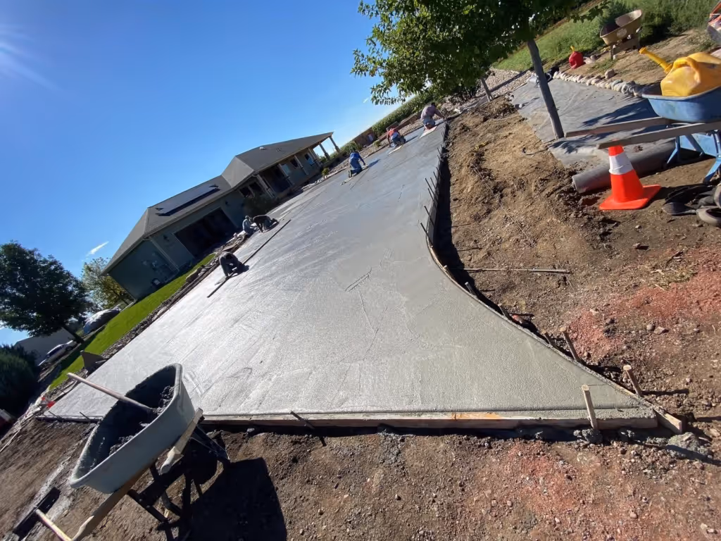 Concrete construction team working on a new driveway with ground compaction in Northern Colorado, showcasing proper site preparation and material handling.