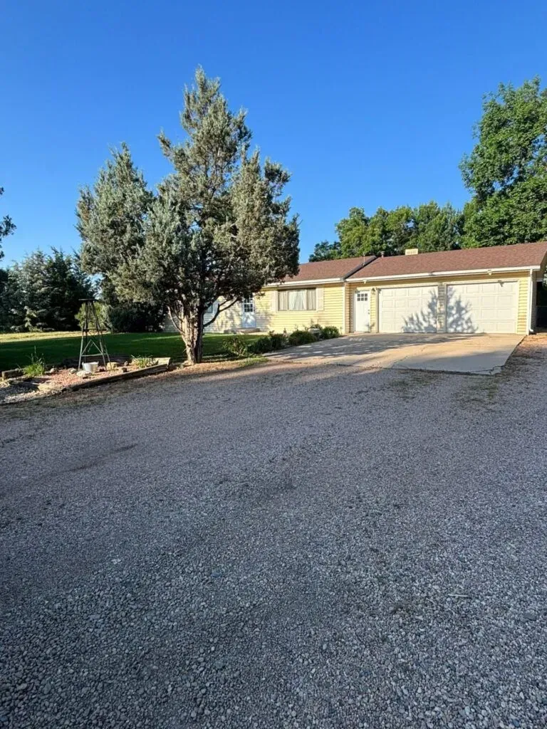 Old cracked concrete driveway with gravel before replacement by Hugo's Concrete in Fort Collins