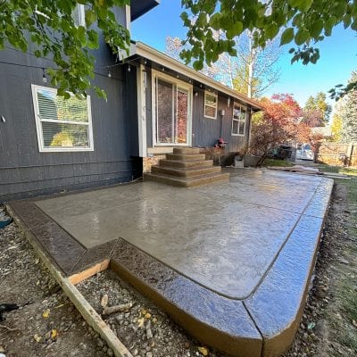 Stamped concrete patio with steps and curved corners installed by Hugo’s Concrete at a residential home in Fort Collins, Colorado.