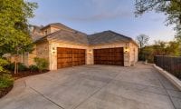 A concrete driveway leading to a two-car garage in a suburban neighborhood.