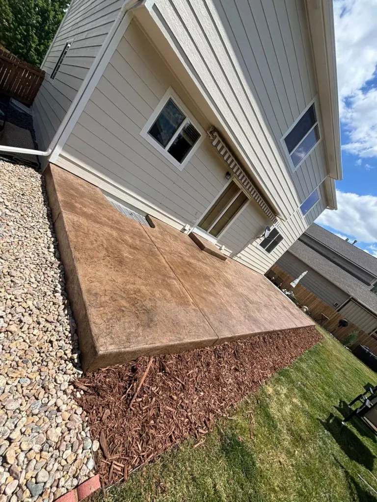 Brand-new light brown stamped concrete patio in Windsor, CO, with a decorative stone-textured finish.