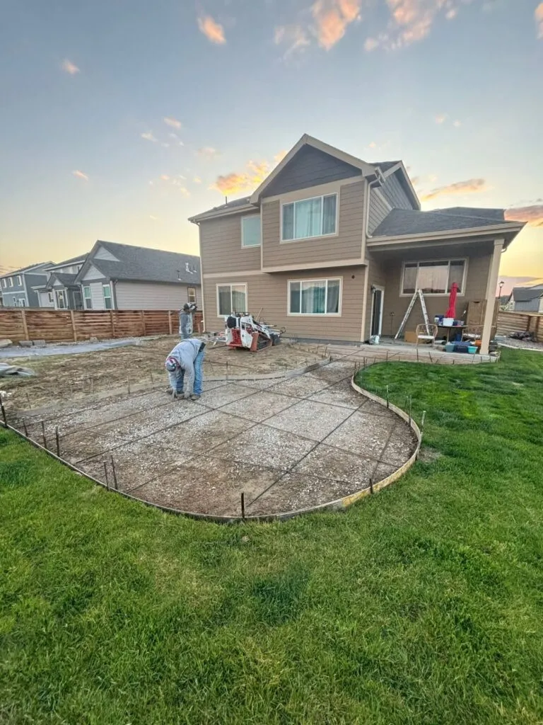 Compacted ground with rebar being installed before concrete walkway and patio pour in Greeley, CO