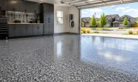 Finished epoxy garage floor with gray flake coating, glossy surface, storage cabinets, and open garage door in a Colorado neighborhood.