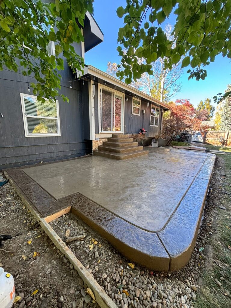 Stamped concrete patio with steps and curved corners installed by Hugo’s Concrete at a residential home in Fort Collins, Colorado.