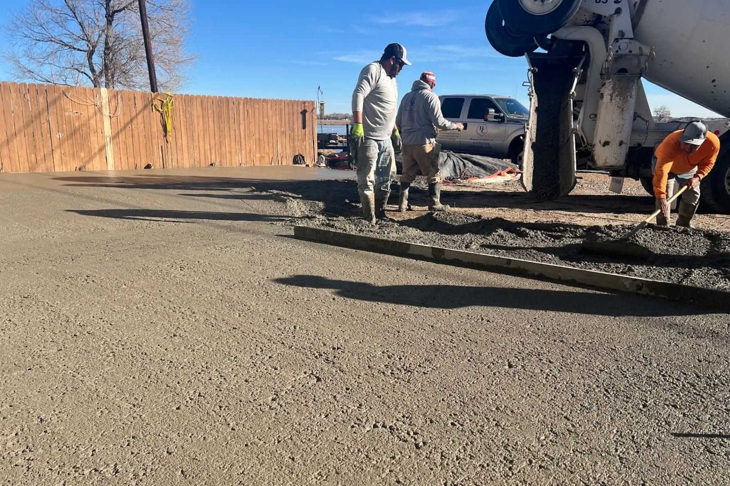 Concrete contractors pouring and screeding 6-inch reinforced 4500 PSI concrete driveway in Windsor, CO, installing heavy-duty slab and driveway extension for RV and heavy vehicle parking.