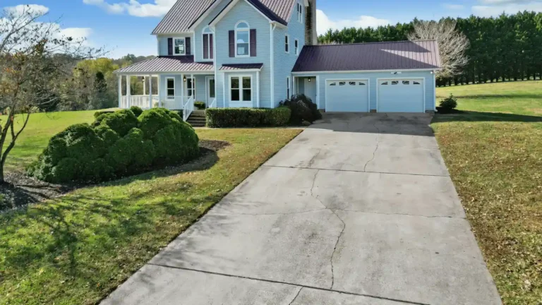 Cracked concrete driveway leading to a residential home with a two-car garage and front porch.