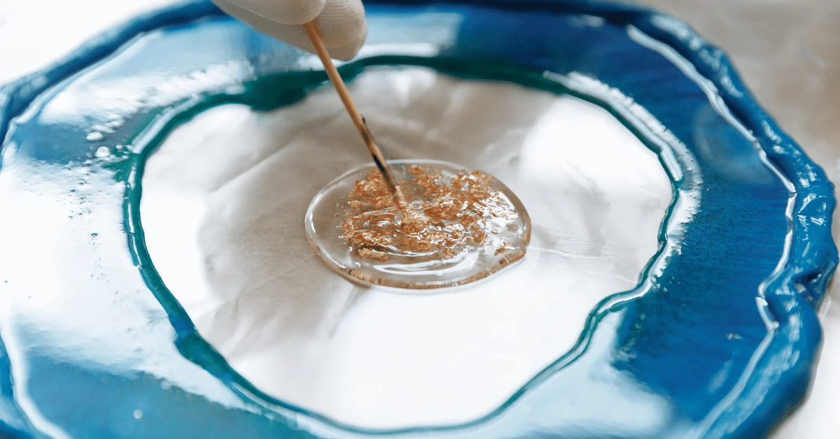 Close-up of glossy blue and clear epoxy resin being mixed for a decorative garage floor coating.
