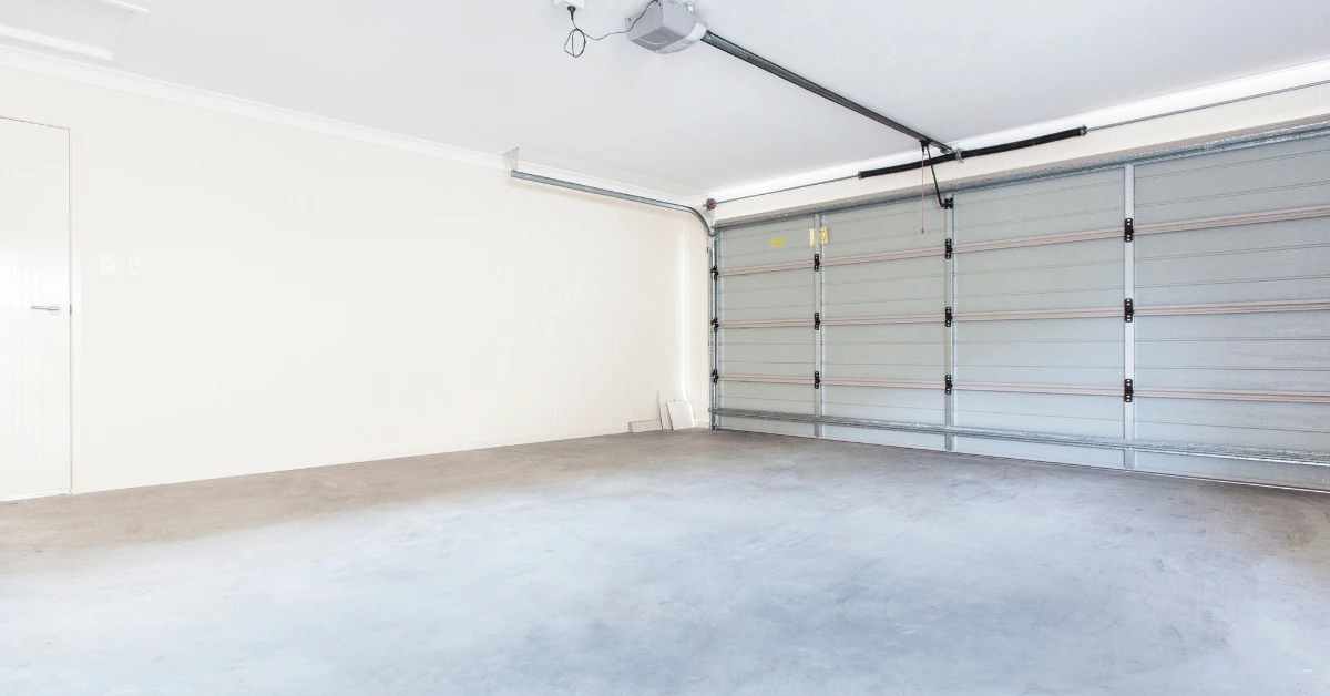 Empty garage with bare concrete floor before epoxy coating, showing a clean surface ready for preparation and finishing.