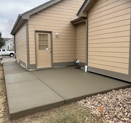 Freshly poured concrete patio and sidewalk next to a Loveland, CO home, showing a newly finished outdoor walkway and slab.