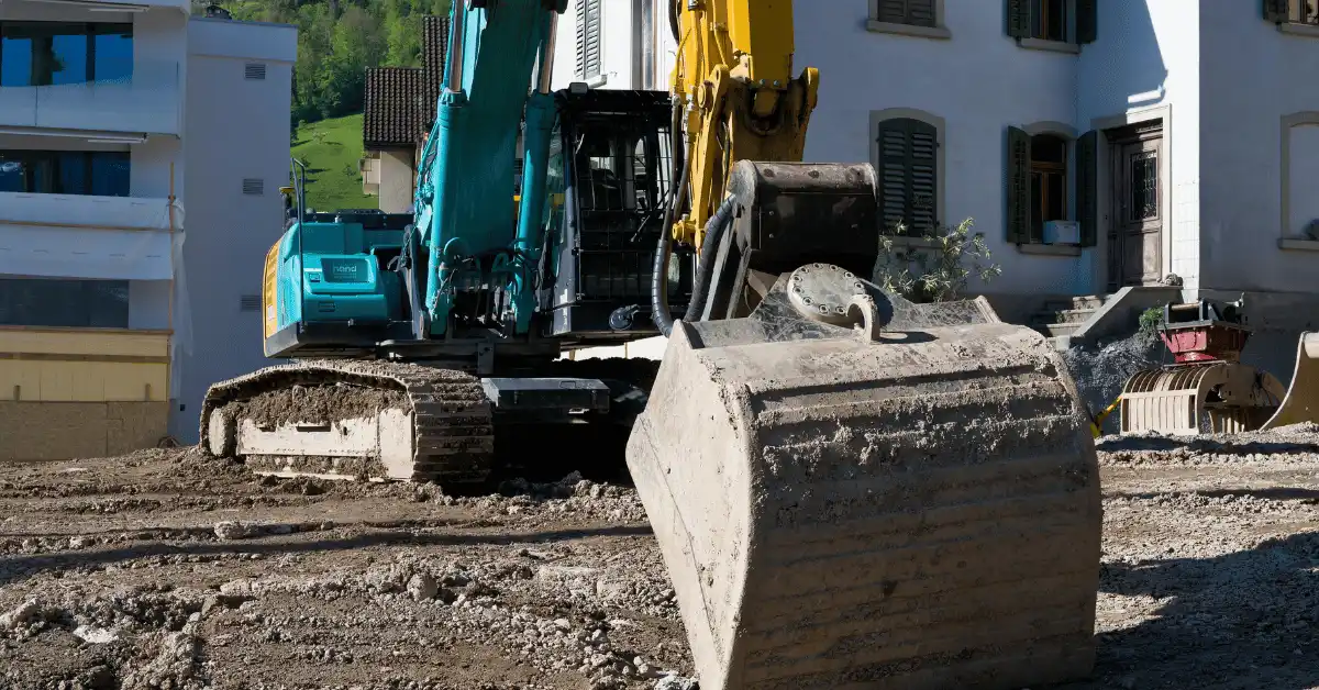 Excavator with a bucket attachment clearing and grading a residential job site before a concrete pour