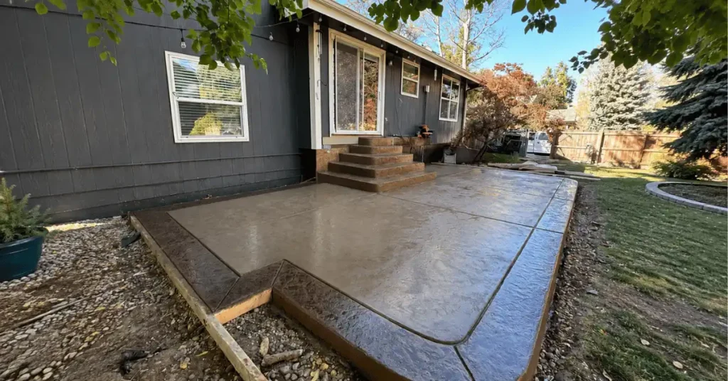 Finished stamped and stained concrete patio with matching steps leading up to a home's back entrance